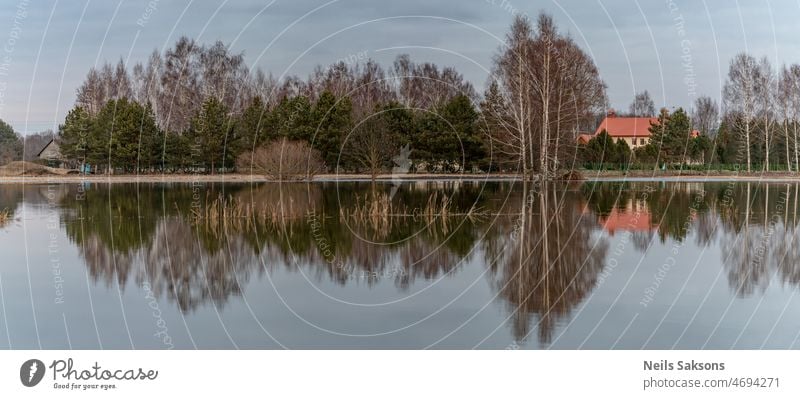 Reflexion von Bäumen, Häusern, im Frühjahr Hochwasser Wasser nach Schneeschmelze im Frühjahr. Überflutetes Feld und Wiese in Lettland, Stadt Jelagava, Fluss Lielupe