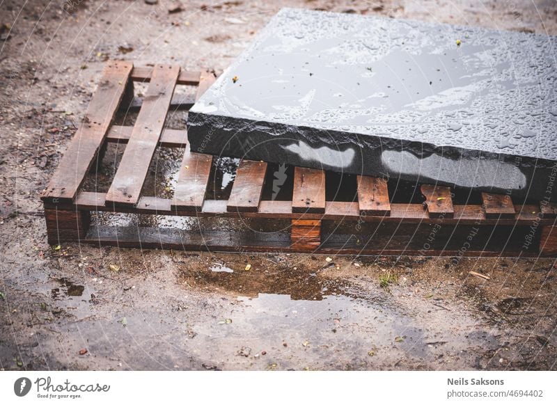 Platte aus schwarzem Granit auf Holzpalette an einem regnerischen Tag Architektur Hintergrund Aufkantung Klotz Zement Konzept Beton Konstruktion Fabrik Stock