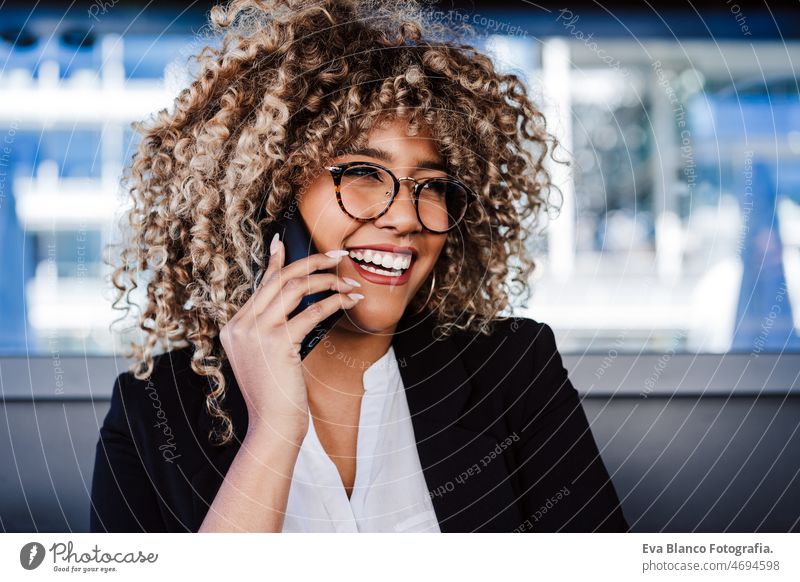 lächelnde hispanische afroamerikanische Geschäftsfrau mit Brille in einem Café, die einen Laptop und ein Mobiltelefon benutzt Computer Afro-Look Frau Business