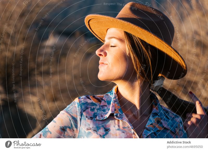 Frau in ht stehend in der Landschaft Stil Natur Sonnenlicht feminin Hut genießen Vorschein ländlich Kopfbedeckung Kopfschmuck verträumt Outfit Bekleidung