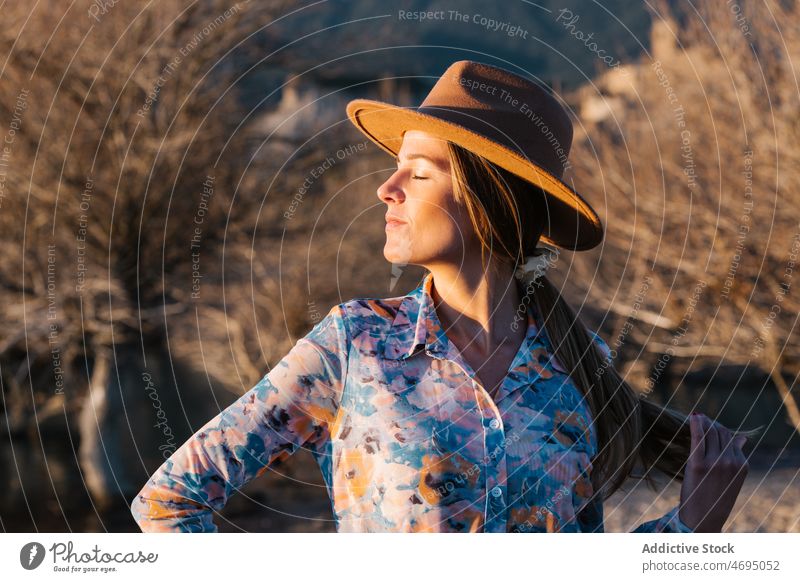 Frau in ht stehend in der Landschaft Stil Natur Sonnenlicht feminin Hut genießen Vorschein ländlich Kopfbedeckung Kopfschmuck verträumt Outfit Bekleidung