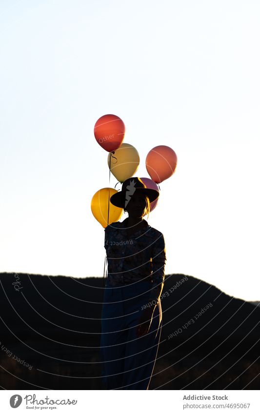 Anonyme Frau mit Luftballons auf dem Lande Silhouette Sonnenuntergang Natur Abend Schatten festlich Zeitvertreib Freizeit Berge u. Gebirge farbenfroh Kamm