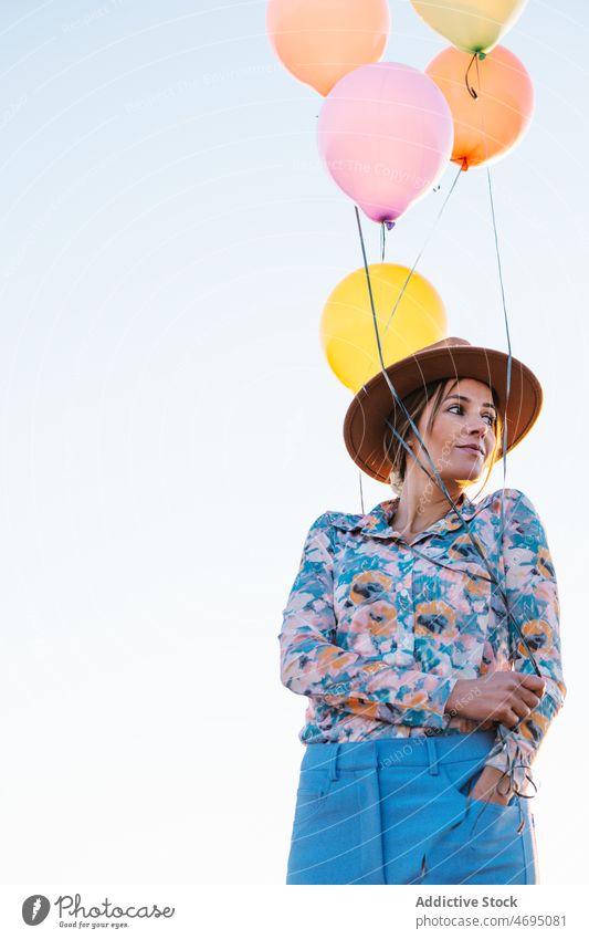 Nachdenkliche Frau mit Luftballons gegen wolkenlosen Himmel Landschaft Natur Stil Hut farbenfroh nachdenklich Sommer hell verträumt Outfit Hafengebiet Ambitus