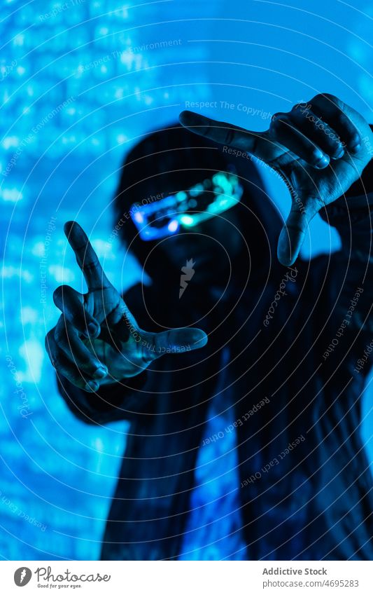 Mann mit futuristischer Brille macht Rahmengeste Cyberpunk Zukunft Hochtechnologie modern trendy gestikulieren Brief Projekt Wand Windstille glühen männlich
