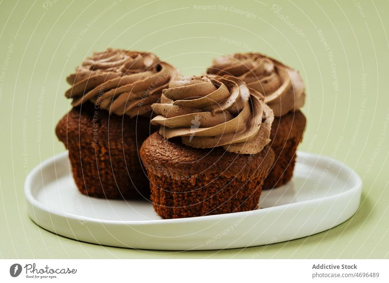 Schokoladen-Cupcakes mit Zuckerguss auf einem Teller Dessert süß Konfekt Gebäck Konditorei Belag Leckerbissen Lebensmittel frisch geschmackvoll lecker