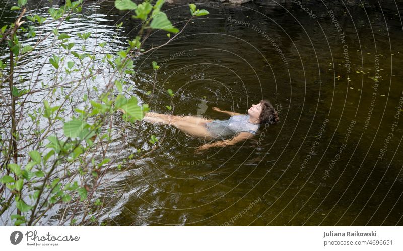 Frau schwimmt entspannt im See Leben Lächeln ästhetisch Umweltschutz Naturverbundenheit Blätter Lebensfreude Zufriedenheit geschlossene Augen Optimismus Freude