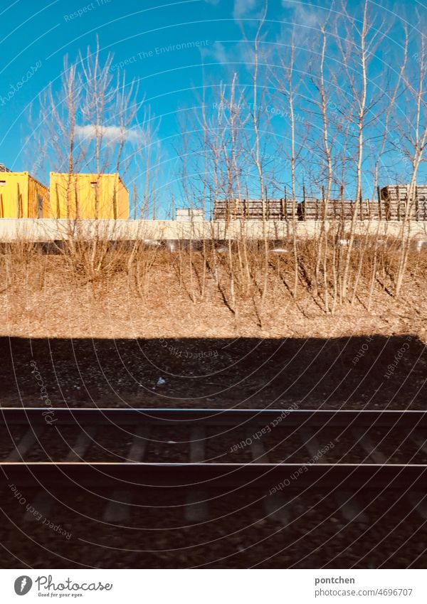 Ein Bahngleis im schatten. Container in der Sonne. Blick aus dem Zugfenster Bahngleiß Zugfahrt Eisenbahn Bahnfahren Verkehrsmittel Schiene