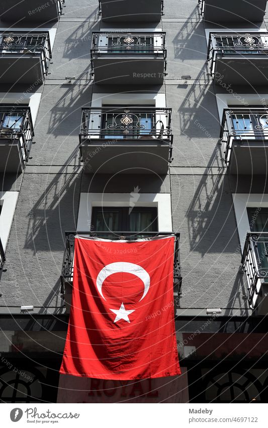 Leuchtend rote türkische Fahne am Balkon eines schönen Wohnhaus mit grauer Fassade im Sommer bei Sonnenschein im Galataviertel im Stadtteil Beyoglu in Istanbul am Bosporus in der Türkei