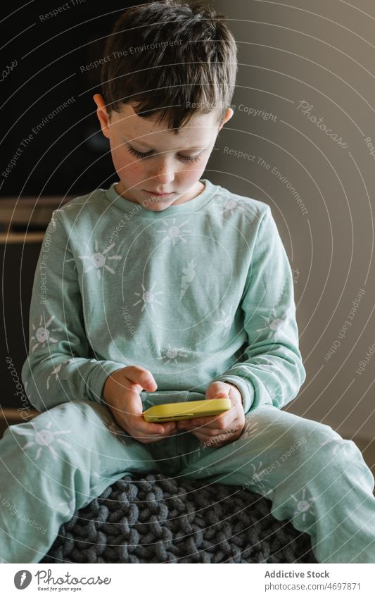 Junge im Pyjama, der auf seinem Smartphone spielt Kind Kindheit Videospiel spielen Zeitvertreib Morgen heimisch Raum Appartement bezaubernd Barfuß flach