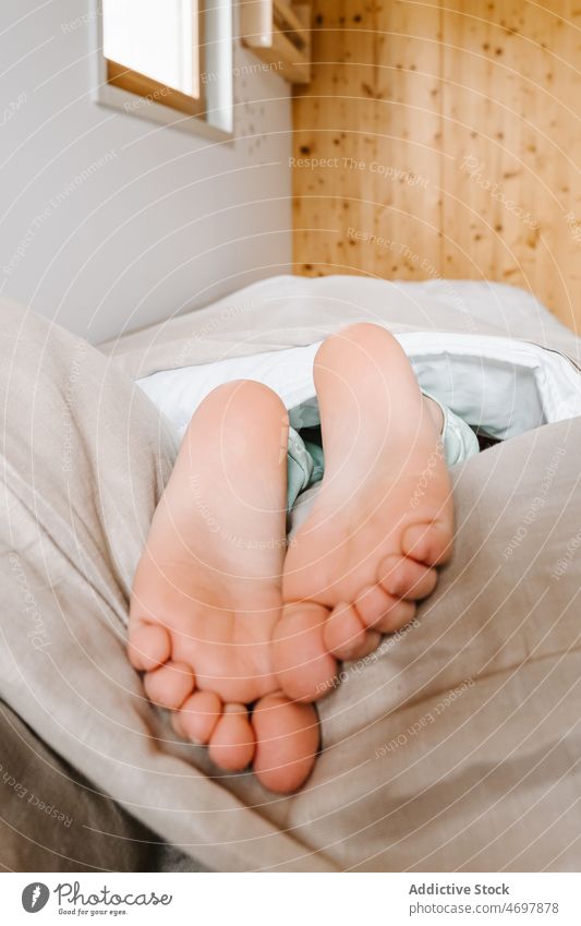 Unbekanntes Kind liegt barfuß im Bett Barfuß wenig Pflege Gesundheit Raum Komfort allein Kindheit Fuß menschlich unverhüllt lässig Kühlung schön schlafen Bein