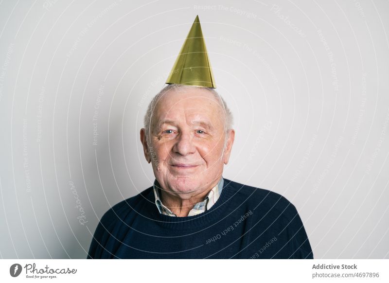 Fröhlicher älterer Mann mit Partyhut im Studio Geburtstag Lachen feiern Feiertag Senior Spaß Freude Glück männlich Hut festlich Spaß haben Humor heiter