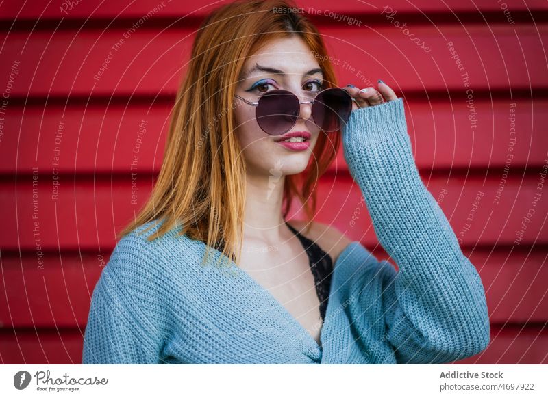 Attraktive Frau setzt Sonnenbrille auf Stil Accessoire Straße Wand Vorschein Streetstyle trendy Design Großstadt charmant Dame anhaben urban Licht feminin Farbe