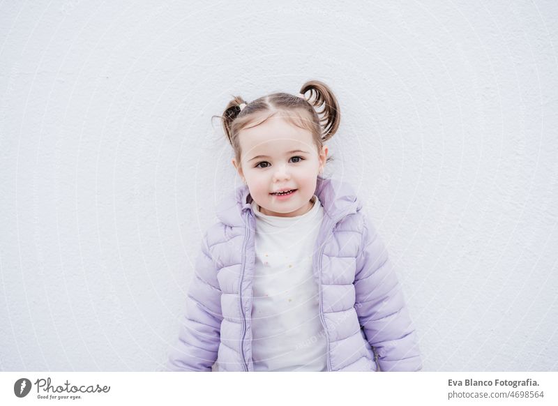 Porträt der schönen kaukasischen zwei Jahre altes Baby-Mädchen lächelnd über weißen Hintergrund. Kindheit im Freien Großstadt Mantel kalt Winter Kaukasier