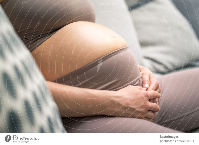 Schwangere Frau Bauch. Schwangerschaft Konzept. Schwangere Bauch Nahaufnahme. Detail der schwangeren Frau entspannt auf bequemen Sofa zu Hause. Liebe schön