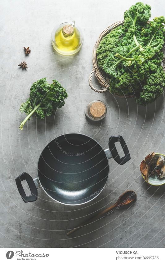 Lebensmittel Hintergrund mit Kochtopf und Grünkohl Blätter leer hölzern Kochlöffel Gesundheit Zutaten roh Kale Olivenöl Sternanis grau Küche Tisch heimwärts