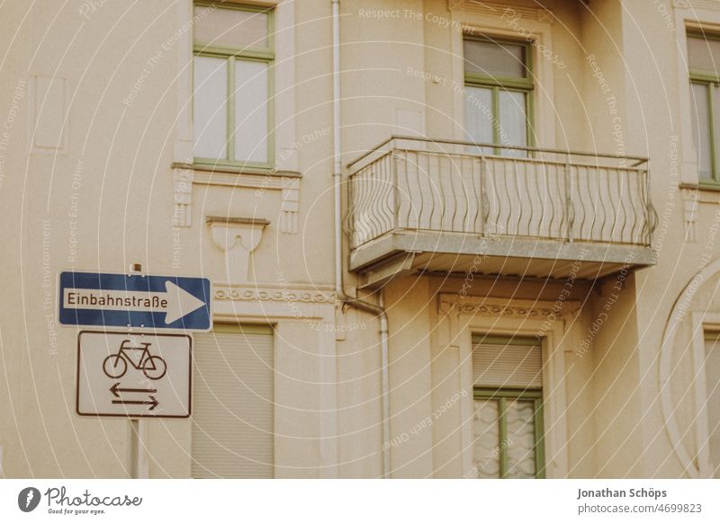 Einbahnstraße Schild vor Fassade Einbahnstraßenschild Verkehrsschild Verkehrszeichen Haus analog retro Fahrradfahren Fahrradweg Balkon beige Altbau Straße