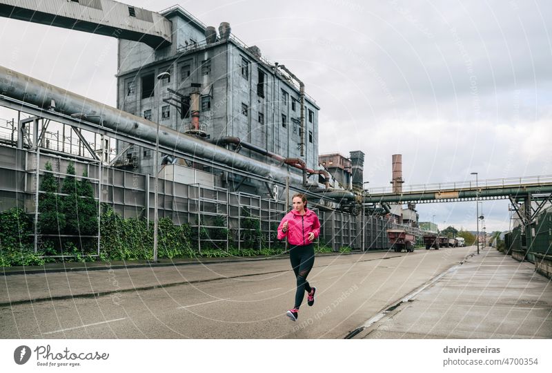 Frau läuft in einem Industriegebiet Läufer Sportlerin Straße rennen industriell Zone Fabrik allein Training Joggen attraktiv schön rosa jung Mädchen einsam