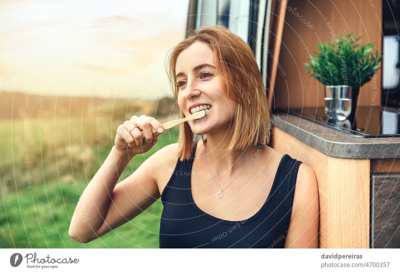 Frau putzt sich die Zähne mit einer Bambuszahnbürste im Freien jung Bürste Zahnbürste Morgen Wohnmobil Kleintransporter Ausflug Lächeln Textfreiraum Gesundheit