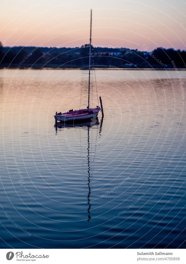 Boot in Abenddämmerung auf einem ruhigen See Wasserfahrzeug Kahn Ruhe Stille still friedlich Friede beruhigend Segelboot Tagesende Abendstille Erholung erholend
