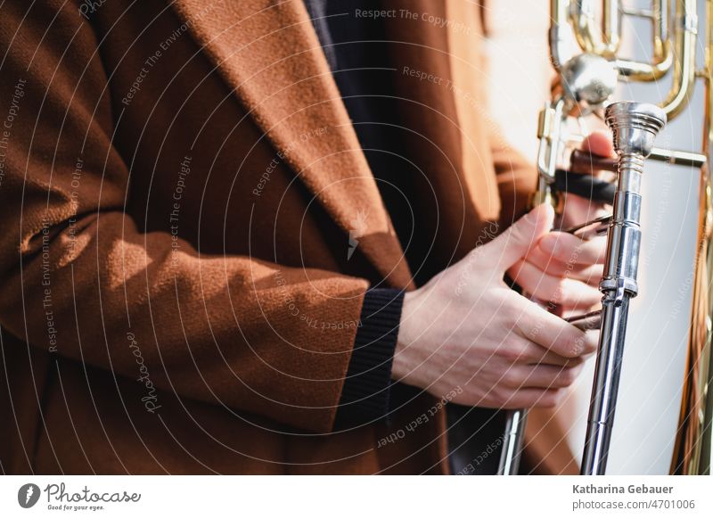 Bann mit rotem Mantel hält Posaune posaunist musiker musik spielen blechblasinstrument musikinstrument bläser Musikinstrument Detailaufnahme
