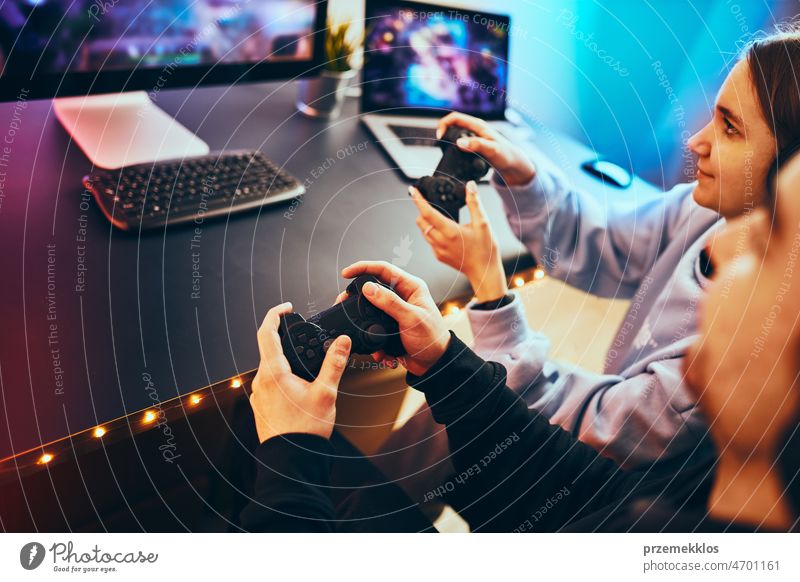 Freunde spielen ein Videospiel zu Hause. Spieler, die online in einem dunklen, von Neonröhren beleuchteten Raum spielen. Wettbewerb und Spaß haben Spielen