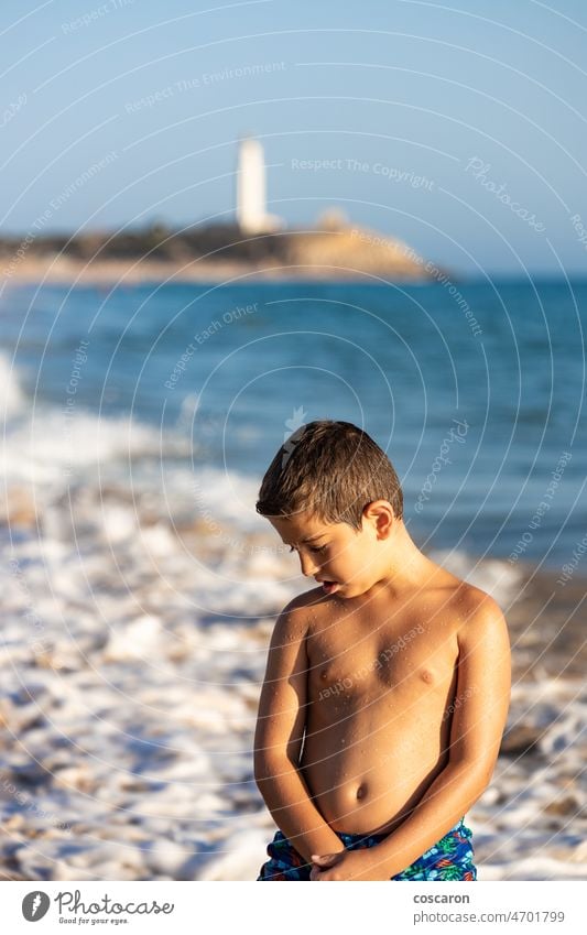 Porträt eines kleinen Kindes am Meer mit einem Leuchtturm im Hintergrund Rücken Barbate Strand Junge Cadiz Küste Küstenlinie Staatsstrand El Matador genießen