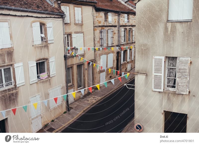 Straße in Frankreich, mit Wimpeln geschmückt für einen Festtag Wimpelkette Fähnchen Häuser fensterläden verlassen Menschenleer Altbau Straßenfest Zickzack