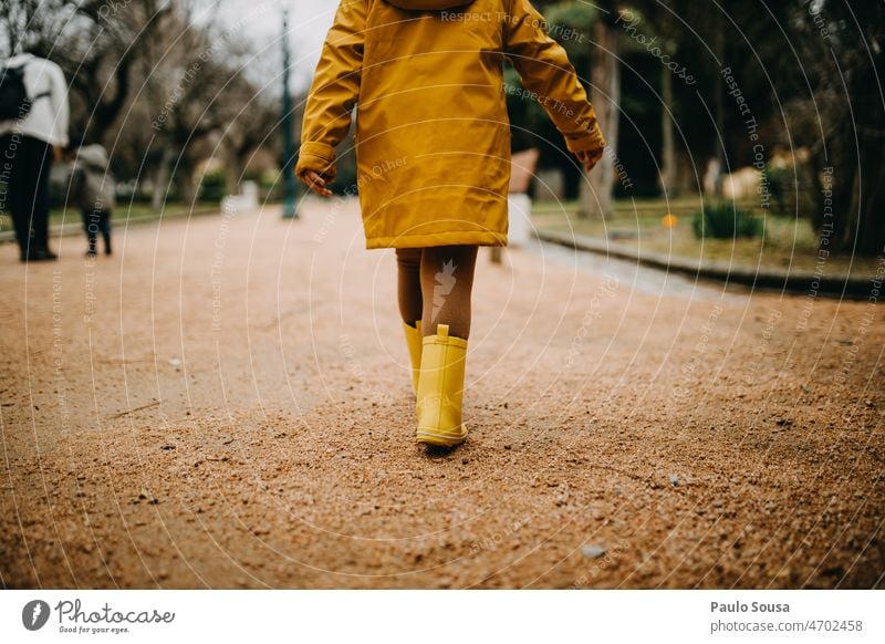 Rückansicht Mädchen mit gelben Gummistiefeln beim Gehen Jacke Kind Kindheit Mensch Außenaufnahme Farbfoto Spielen Tag Freude nass 1 Regen authentisch Pfütze