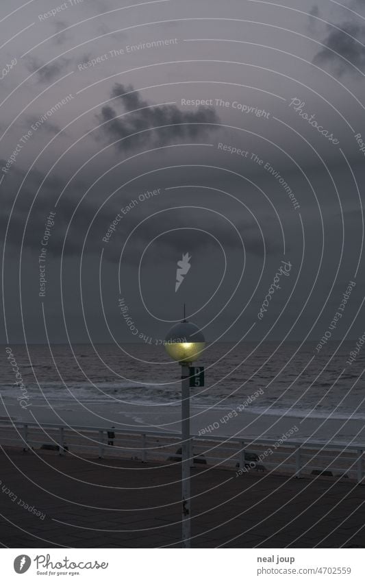 Straßenlampe in der Dämmerung, die genau den Meersehorizont schneidet Landschaft Küste Abend Licht Geometrie Linie Horizont düster trüb grau stürmisch Sturm