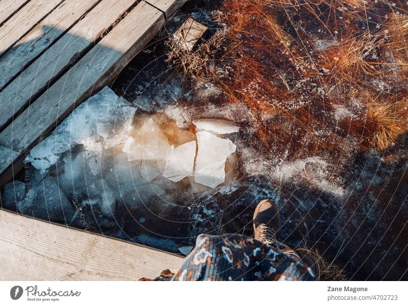 Eine Frau sitzt am zugefrorenen Fluss, Vorfrühling, schmelzendes Eis im Freien Holz Frühling Schmelzen Eisschmelze Sonnenlicht Kontrast Tageslicht