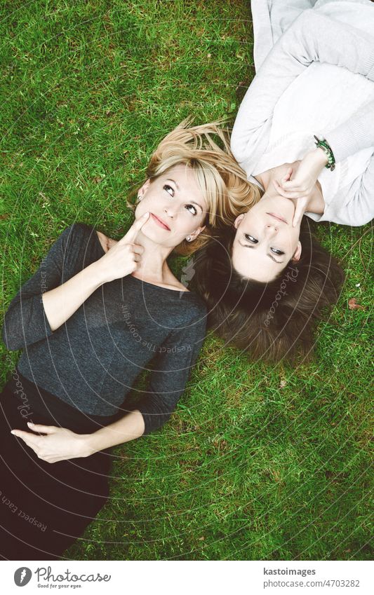 Zwei nachdenkliche Mädchen liegen im Gras Frauen Vernehmung Tagträumen Freunde Fragen Denken schön Hintergrund Schönheit blond Brainstorming brünett Kaukasier