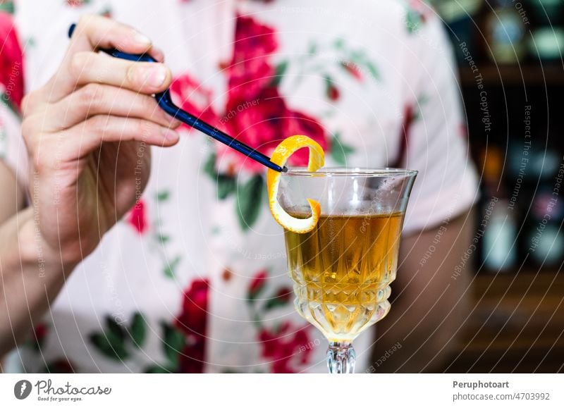 Barkeeper dekoriert ein Glas mit einem frischen alkoholischen Cocktail auf dem Bartresen, Nahaufnahme. Barmann Restaurant Schnaps Mixologe Nachtleben Eis orange