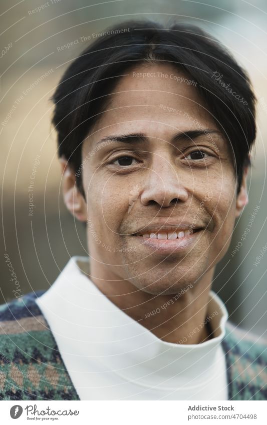 Lächelnder ethnischer Mann mit schwarzen Haaren und im Pullover positiv Vorschein Stil Porträt Individualität Persönlichkeit Haarschnitt Jacke heiter