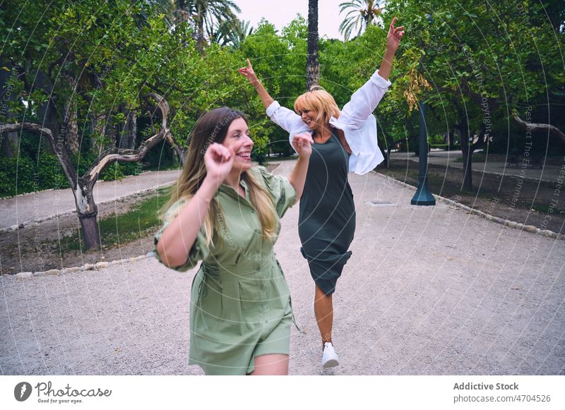 Positive Frauen gehen im Park spazieren Freundschaft Bonden Partnerschaft Zeit verbringen Spaß haben genießen Zeitvertreib Zusammensein Großstadt Baum Freundin