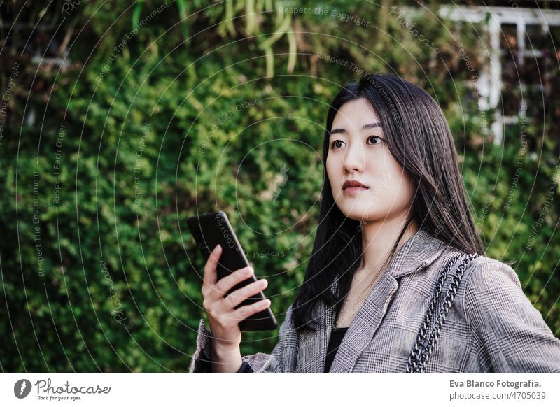 Porträt einer schönen chinesischen Geschäftsfrau, die in einem Bürogebäude ein Mobiltelefon benutzt. Technik Chinesisch asiatisch Frau Laptop