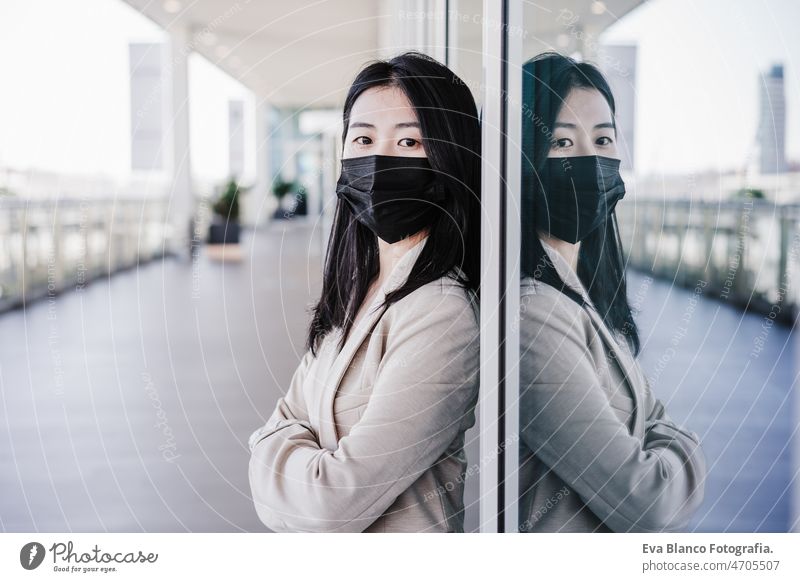 junge geschäftsfrau mit gesichtsmaske in der stadt. corona virus konzept Chinesisch Frau Gesichtsmaske Corona-Virus Pandemie Büro Zusammenarbeit Glas