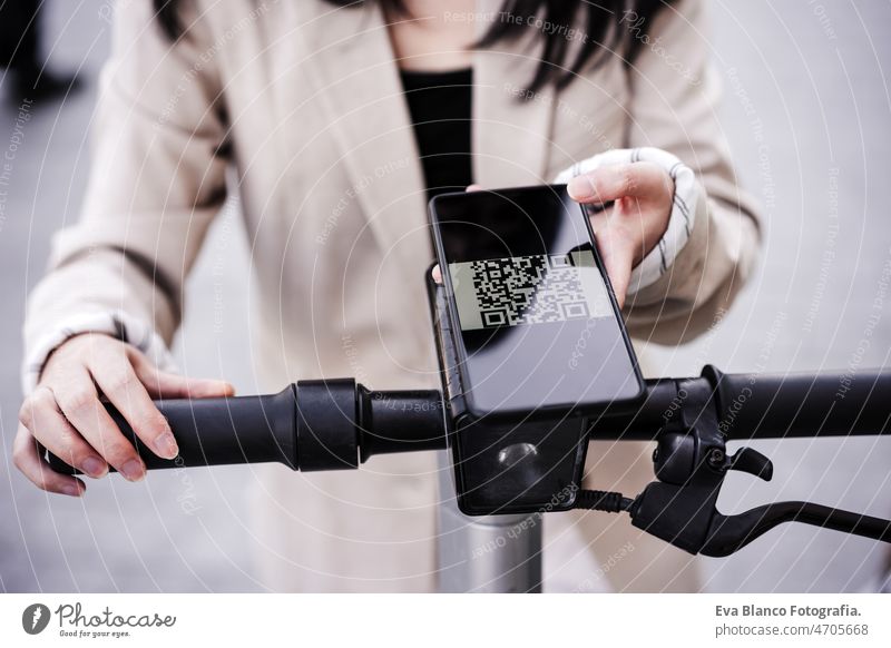 Geschäftsfrau entriegelt Elektro-Scooter per Smartphone auf der Straße. nachhaltiger Verkehr qr-Code Freigabe unkenntlich berühren Drahtlos Vermietung asiatisch