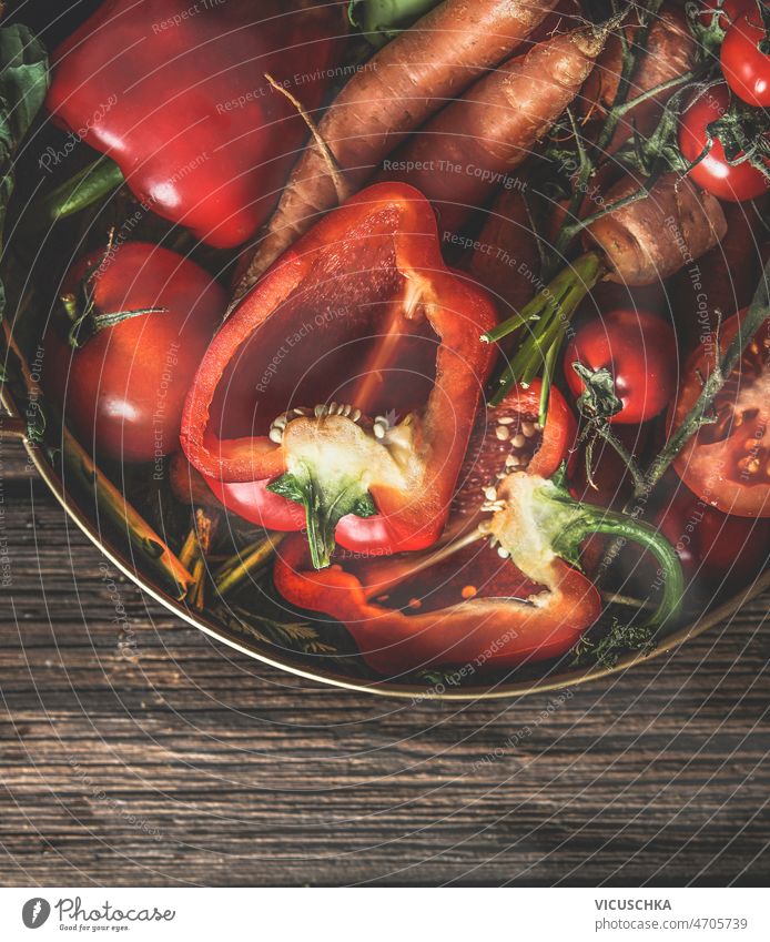 Nahaufnahme verschiedener roher roter Gemüsesorten in einer Schüssel an einem rustikalen Tisch abschließen orange Sommer Schalen & Schüsseln hölzern halbiert