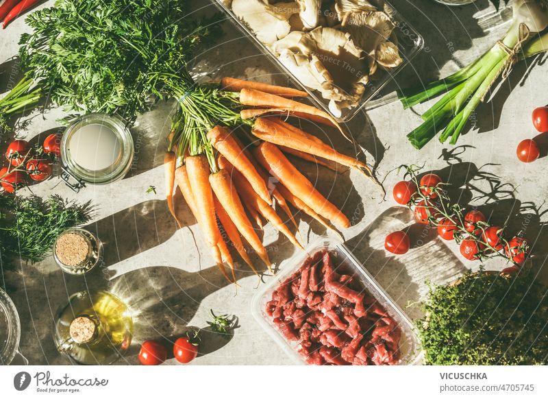 Lebensmittel Hintergrund mit verschiedenen gesunden Kochen Zutaten auf Küchentisch Rohfleisch grau Tisch Sonnenlicht Karotten Tomaten Erdöl Frühlingszwiebeln