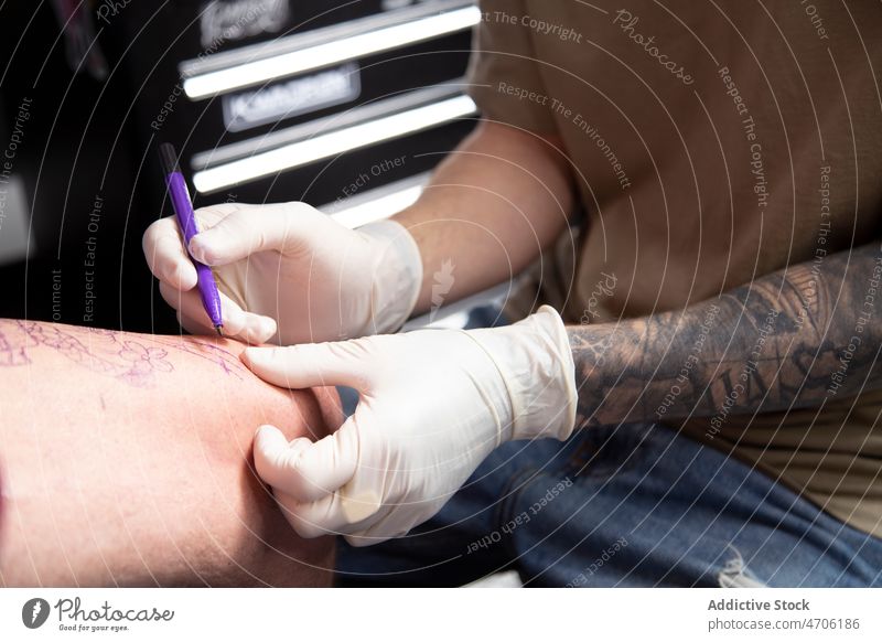 Anonymer Tätowierer zeichnet Skizze auf das Bein eines Kunden Klient Tattoo Schreibstift Meister freie Hand Salon zeichnen Design Tiefgang professionell Arbeit