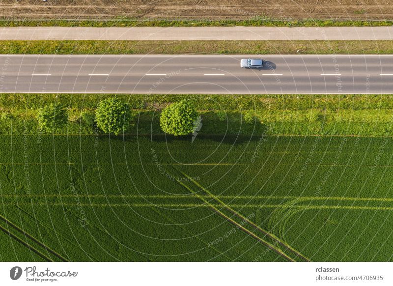 Luftaufnahme einer zweispurigen Straße durch ländliche Gebiete und bewirtschaftete Felder mit Autos. Drohnenaufnahme und Kopierraum für Text Dröhnen Fernstraße