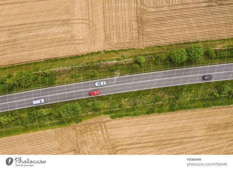 Luftaufnahme des Verkehrs auf einer zweispurigen Straße durch eine ländliche Gegend und bestellte Felder Dröhnen Fernstraße Ausflug landwirtschaftlich