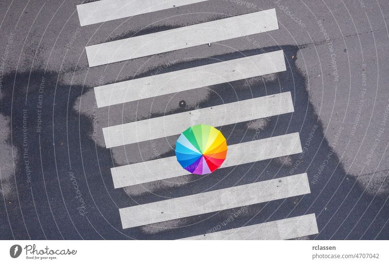 Regenbogenschirm auf einem Fußgängerüberweg - Blick aus einer Drohne Regenschirm Top Überfahrt Ansicht Farbe Zebrastreifen Dröhnen Straße Großstadt laufen