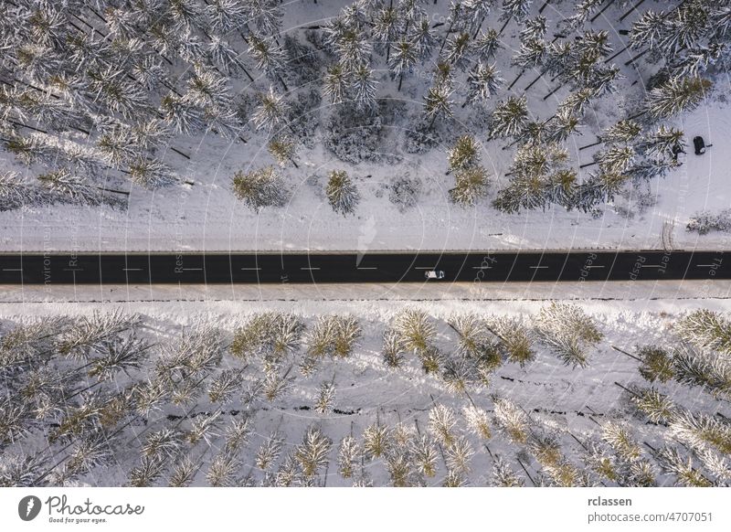 Winterlich verschneite Kiefernwälder und Straße mit Auto aus der Vogelperspektive Wald Dröhnen Antenne Sonnenuntergang Sonnenlicht Ansicht oben Flug Tag PKW