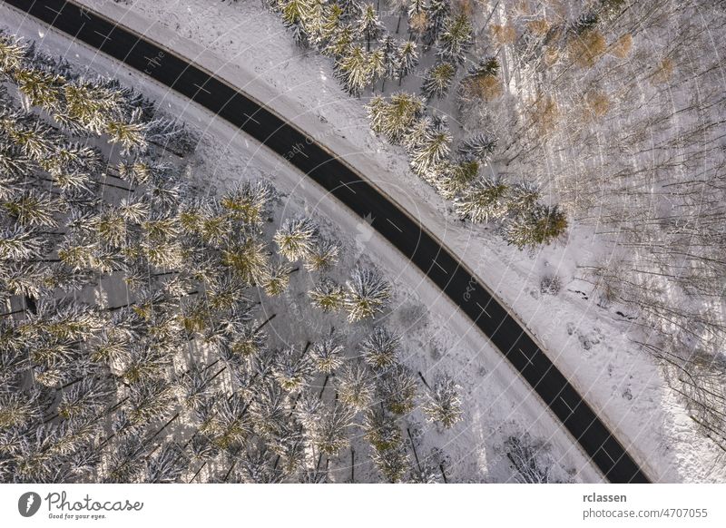 Luftaufnahme einer Winterstraße im verschneiten Wald. Drohne gefangen Schuss von oben Straße Dröhnen Antenne Sonnenuntergang Sonnenlicht Ansicht Flug Tag Kurve