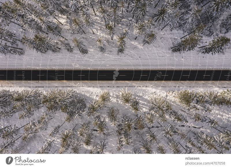 Drohnenaufnahme einer Straße in idyllischer Winterlandschaft bei Sonnenuntergang. Straße läuft durch die Natur aus der Vogelperspektive Wald Dröhnen Antenne