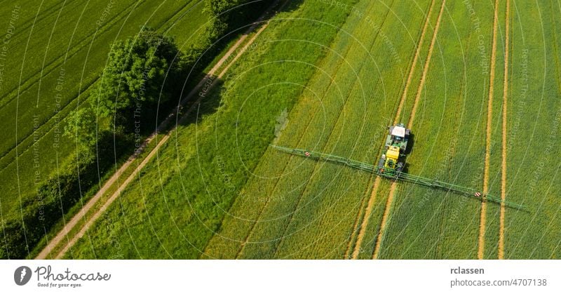 Luftaufnahme eines Traktors beim Sprühen auf dem Feld. Chemie in der Landwirtschaft aus der Drohnenperspektive. Moderne Landwirtschaft Hintergrund Konzept.