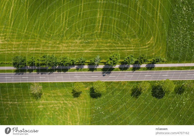 Luftaufnahme einer zweispurigen Straße durch eine ländliche Gegend und bewirtschaftete Felder. Drohnenaufnahme und Kopierraum für Text Dröhnen Fernstraße