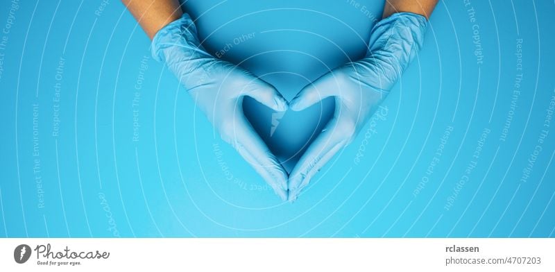 Hände eines Arztes in medizinischen Handschuhen in Form eines Herzens auf blauem Hintergrund, mit Platz für Ihren individuellen Text. Bund 19 Virus Korona
