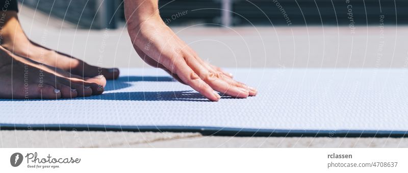 Frau beginnt Dehnübungen auf einer Yogamatte im Freien, mit Schwerpunkt auf den Händen. copyspace für Ihren individuellen Text. Dehnung Unterlage Pilates